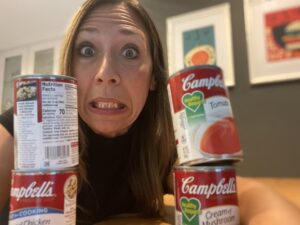 worried woman with cans of soup