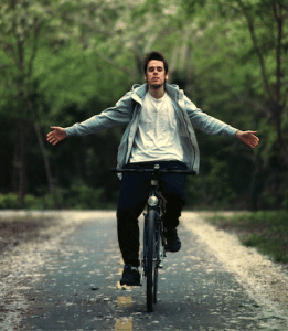 man riding his bike with his arms stretched out to the side in a relaxed position