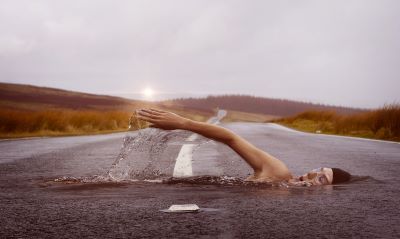 Abstract image of lady swimming across and within a road