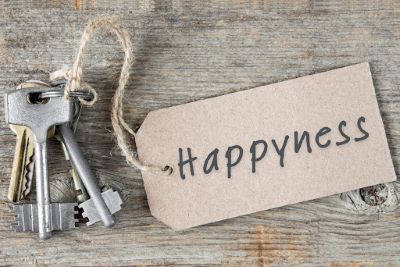 Photo of a bunch of keys on a table top with a label attached to them that reads 'Happyness'