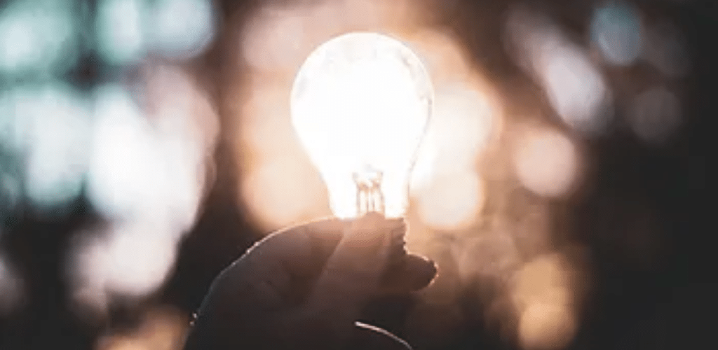 Image of a lit up lightbulb being held in someone's hand