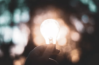 Image of a lit up lightbulb being held in someone's hand